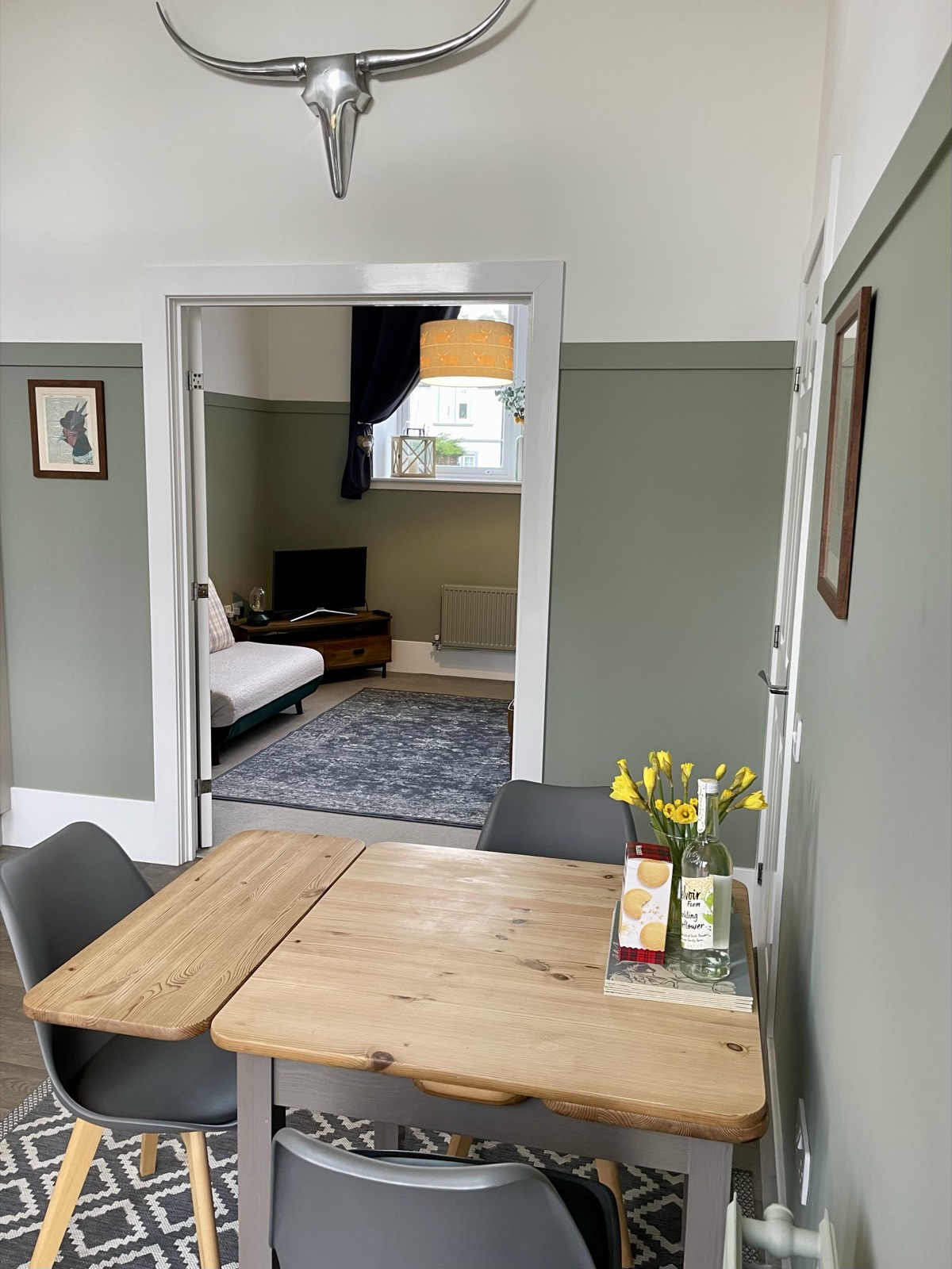 Dining room with cow-skull wall art and double doors to the living room