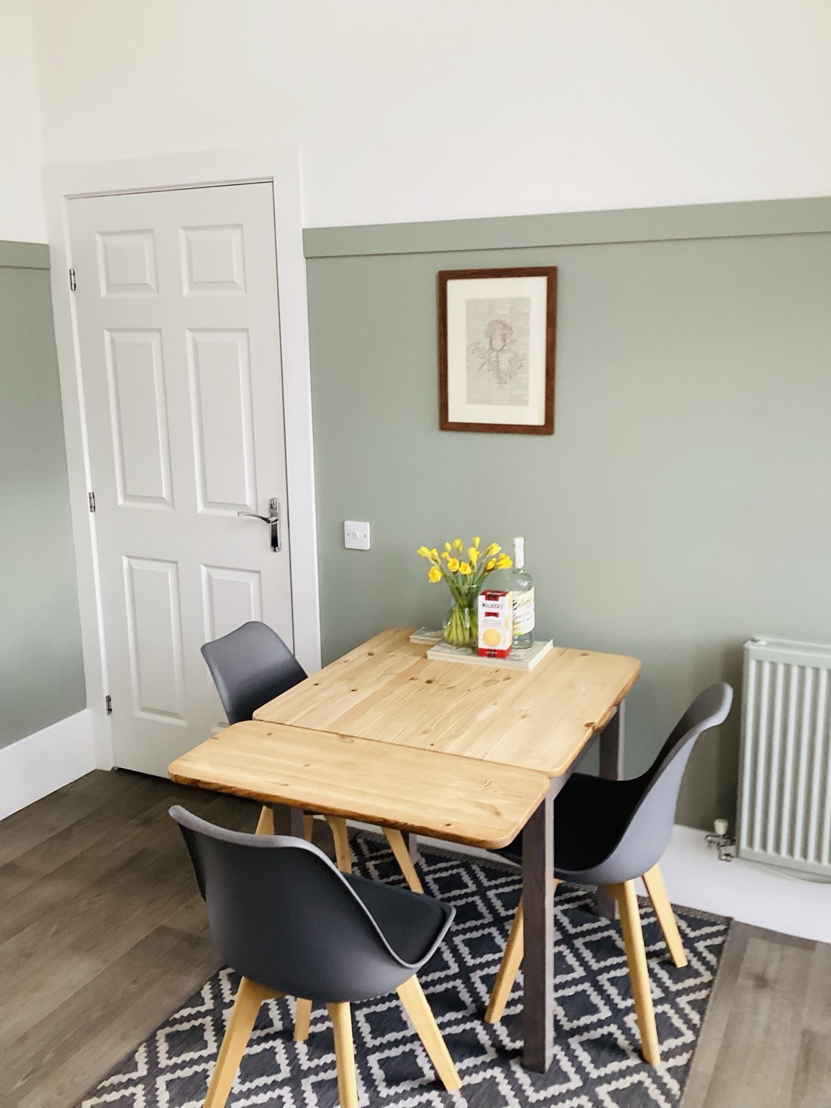 Pine dining table with yellow tulips in the sage green dining room